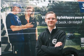 Person som står framför en skåpbil med Husqvarna-logotypen och robotgräsklippargrafik.
