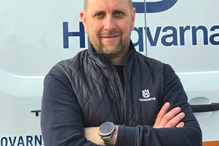 A person standing in front of a vehicle with Husqvarna branding, wearing Husqvarna workwear.