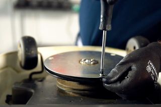 Une personne se sert d’un tournevis pour régler un composant d’une tondeuse.