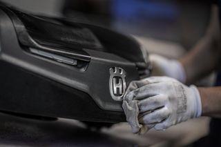 En person som rengör en produkt med Husqvarnas logotyp med en trasa.