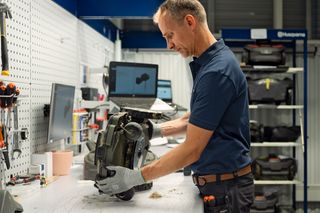 Henkilö, joka tarkastaa robottiruohonleikkuria työpajaympäristössä.