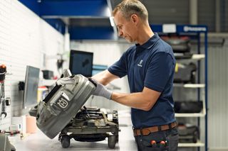 Une personne travaillant sur un robot tondeuse dans un atelier.